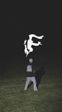 a man is flying a frisbee in a field at night