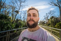 a man with a beard standing on a bridge